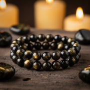 Golden Obsidian Bracelet on dark wood with golden obsidian stones and candlelight